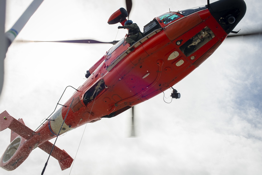 A Coast Guard Air Station New Orleans MH-65 Dolphin aircrew lowers a rescue swimmer during training on Lake Pontchartrain in May 2021. Coast Guard aircrews remained on scene Monday to help account for everyone aboard the burning vessel. File photograph.